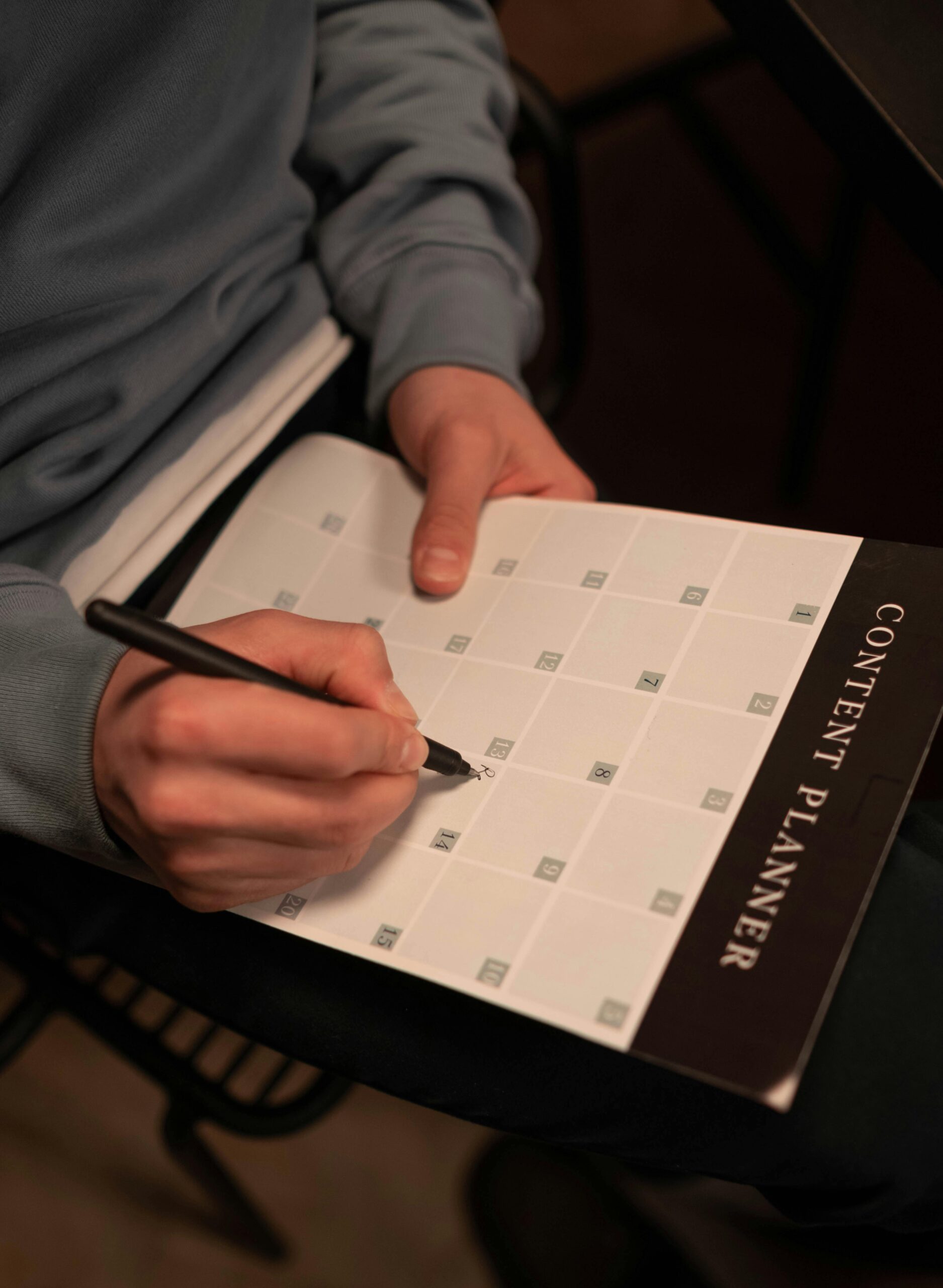 Close-up of a person making notes on a content planner indoors.
